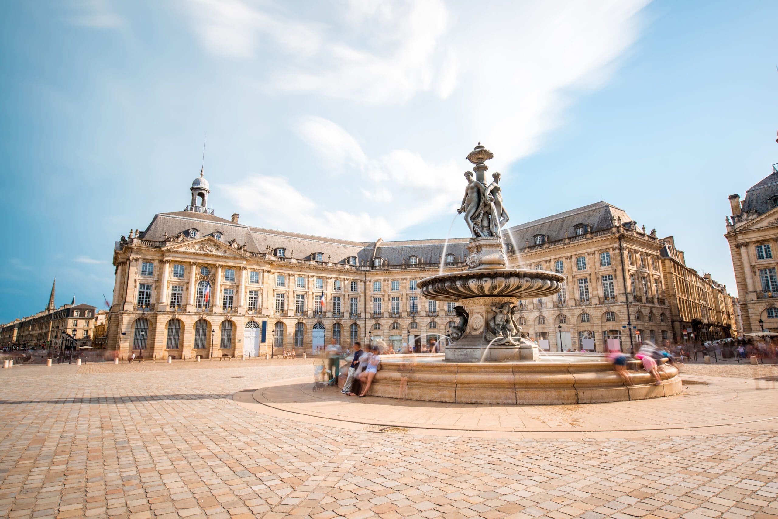 View on the famous La Bourse square with fountain in Bordeaux city, France. Long exposure image technic with motion blurred people and clouds